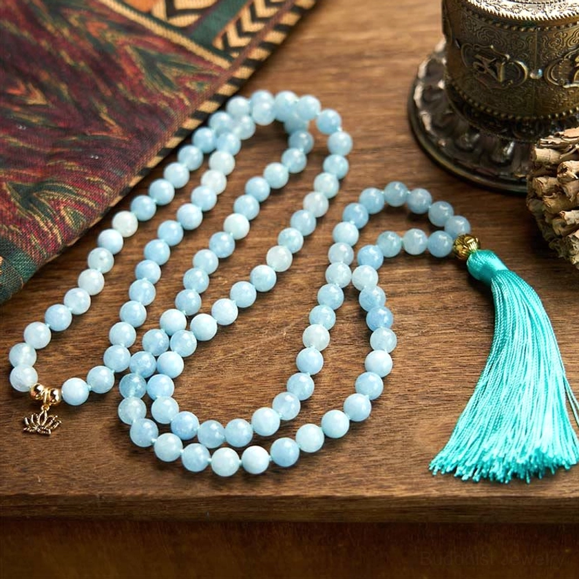 Long aquamarine mala bracelet strands arranged on vintage wooden table with gold accents