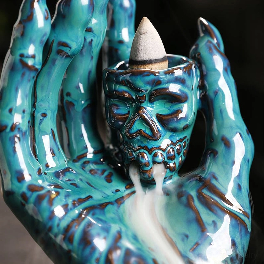 Artisan-made ceramic skull hand incense holder with intricate design details