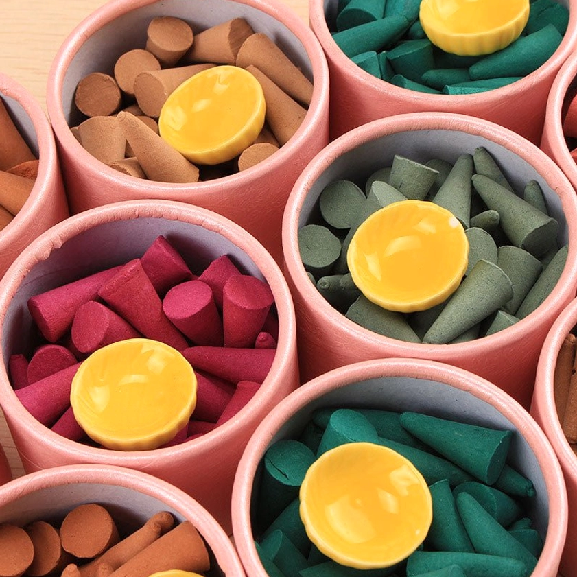 Close-up of multiple incense cone jars displaying brown red green cones with yellow tray inserts