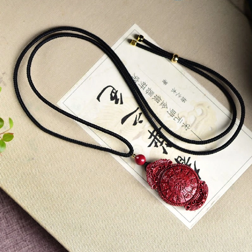Authentic cinnabar Buddhist necklace pendant with laughing Buddha carving displayed on natural background with spiritual ambiance