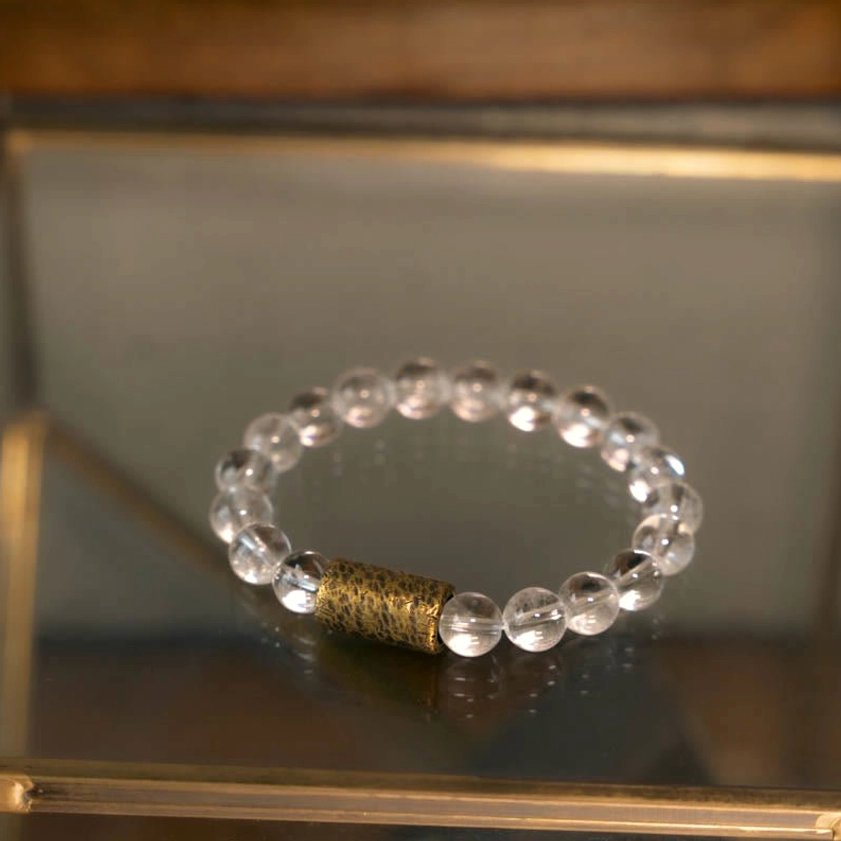 Clear quartz beaded bracelet on mirrored tray with wooden frame showing polished transparent beads