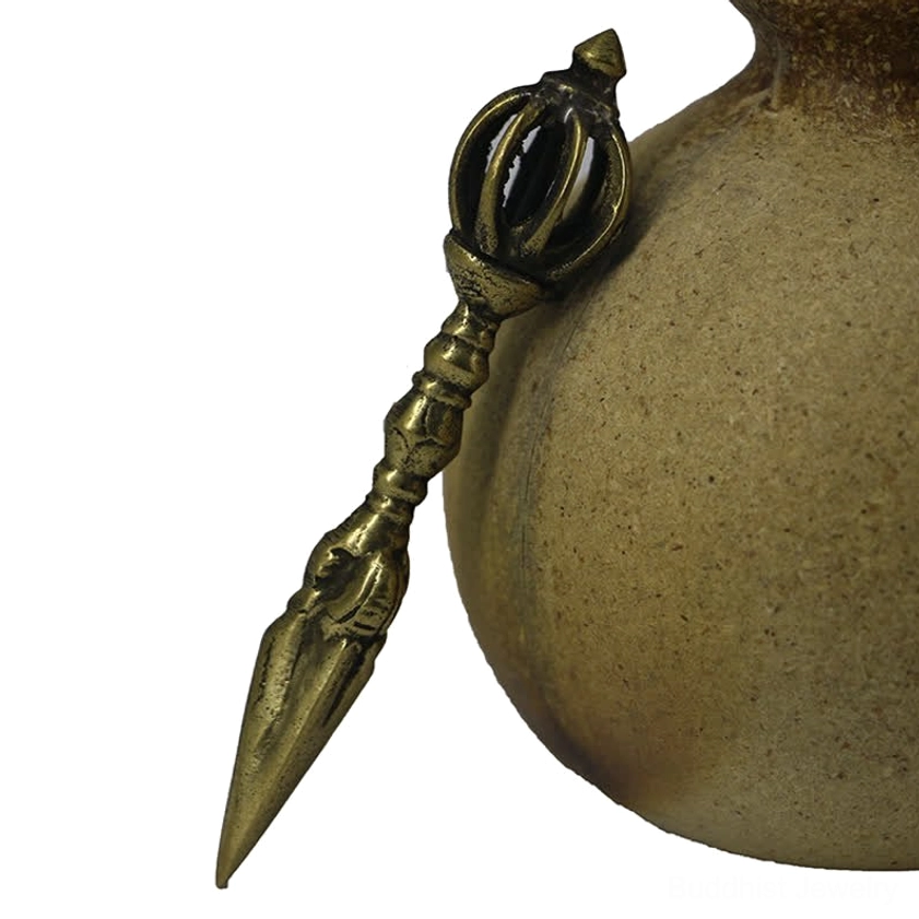 Traditional handmade vajra dorje with dark aged bronze finish and ornate nine-pronged top, leaned against ceramic vessel on bamboo surface