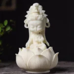 Hand-carved Avalokitesvara Buddha statue with lotus base, front oblique view showing intricate carved details and cream-white finish