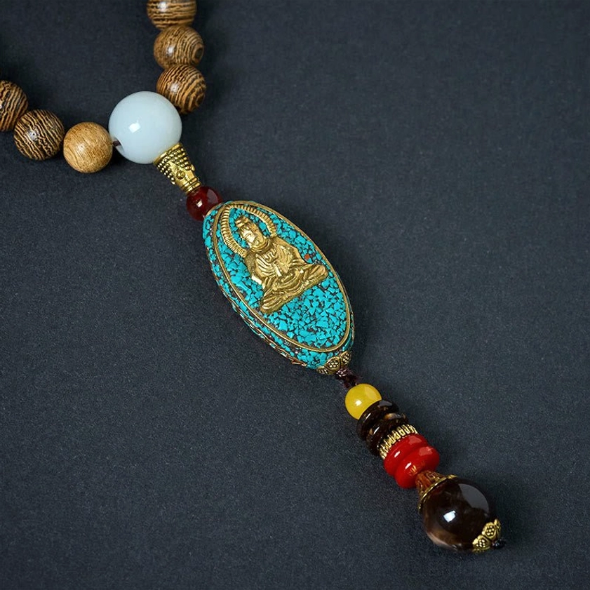 Avalokitesvara pendant necklace detail shot featuring turquoise Buddha charm, multicolor tassel and wooden beads