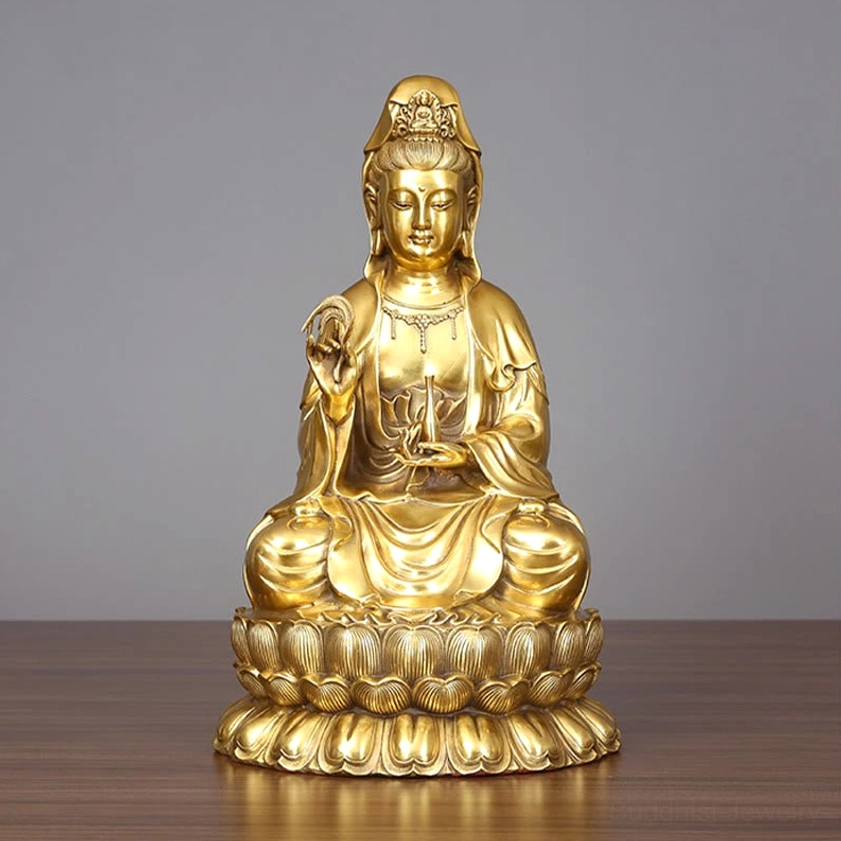 Avalokitesvara Guanyin brass statue with golden finish and willow sprig on wooden display with gray backdrop