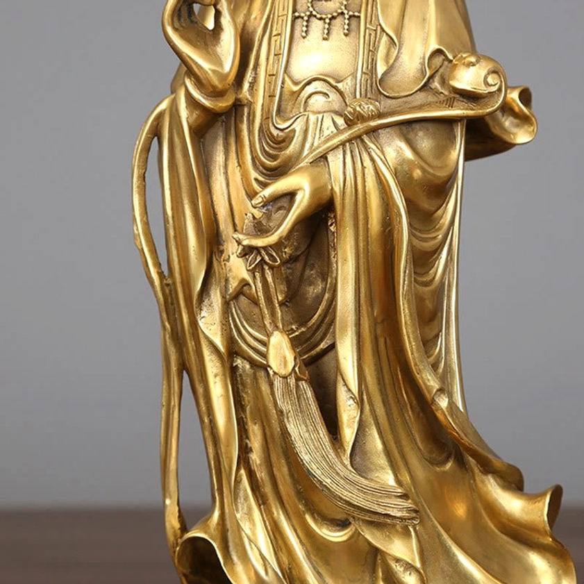 Detailed close-up of Avalokitesvara hand holding ruyi scepter with carved fabric folds and golden metal tassel decorations