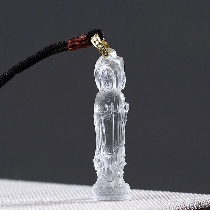 Clear transparent Avalokitesvara crystal glass pendant with black braided lanyard and gold clasp, close-up view