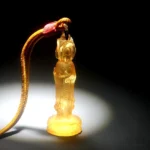 Avalokitesvara Liuli glass pendant necklace in golden amber yellow with braided cord and red fastener, front close-up view
