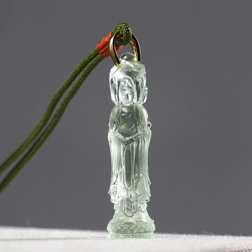 Pale green translucent Avalokitesvara Liuli glass pendant with green braided cord and metal clasp, front close-up