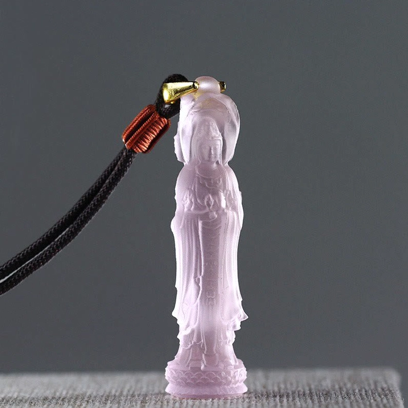Pale pink translucent Avalokitesvara Liuli glass pendant with black braided lanyard, close-up front view
