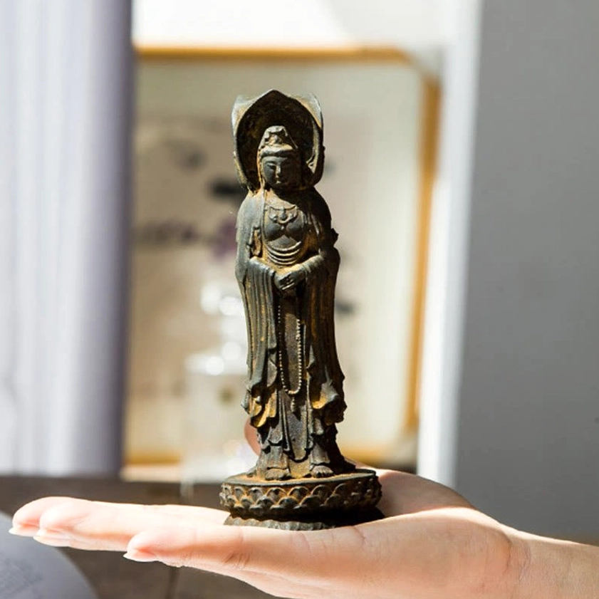 Triple-face Guan Yin statue held in palm showing compact size and intricate detailing