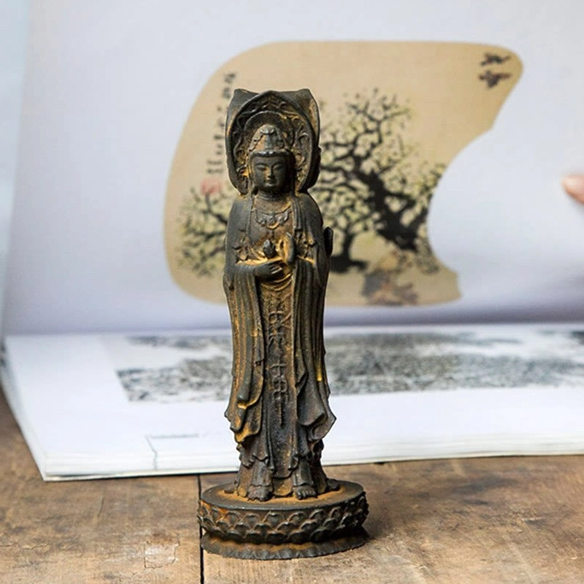 Triple-face Guan Yin statue displayed on wooden desk with Chinese painting background and dark patina