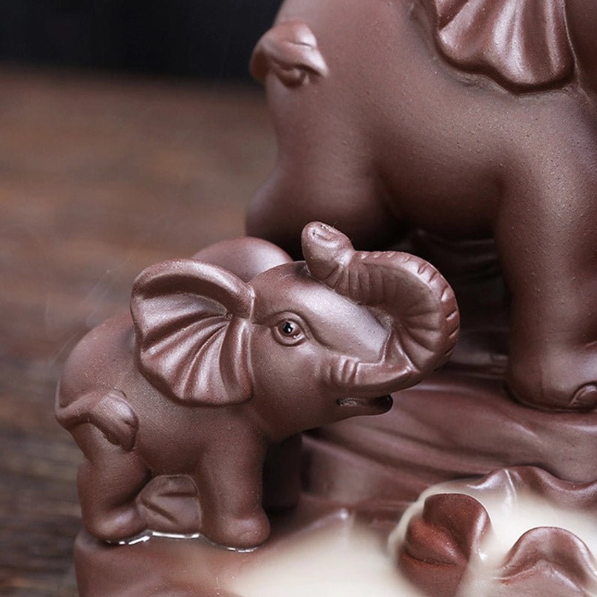 Baby elephant figurine on backflow incense censer with smoke channel, low angle close-up