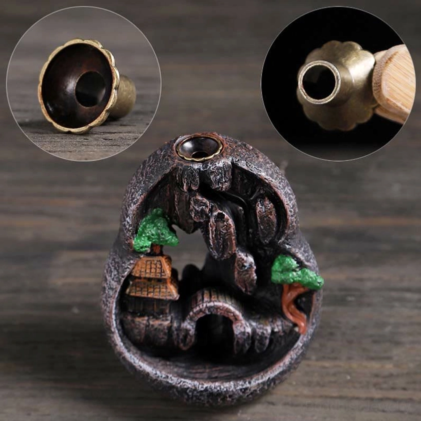 Backflow incense holder with brass socket and miniature village resin decor on display