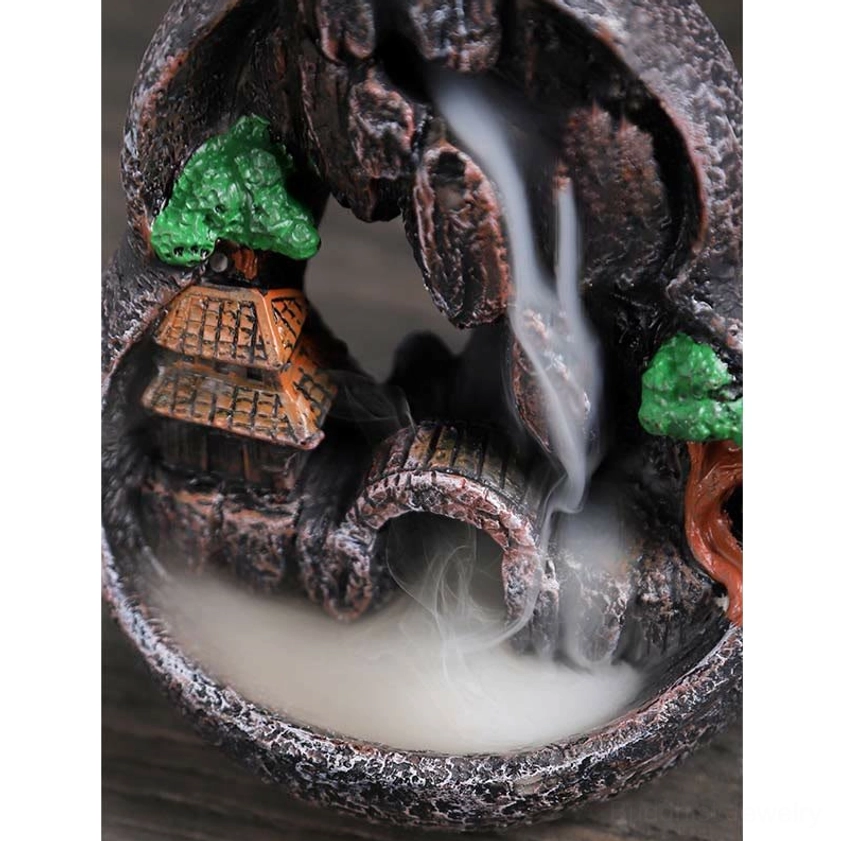 Low-angle view of backflow incense burner interior with miniature arched bridge and flowing smoke