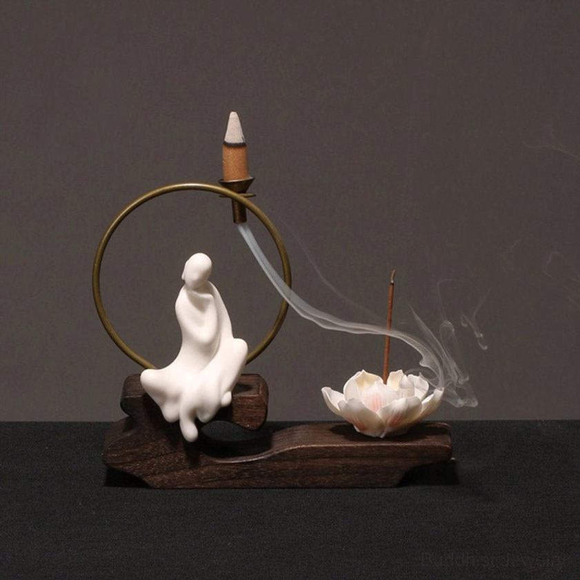 Profile view seated monk backflow incense burner with flowing incense smoke and wooden base, Zen meditation décor