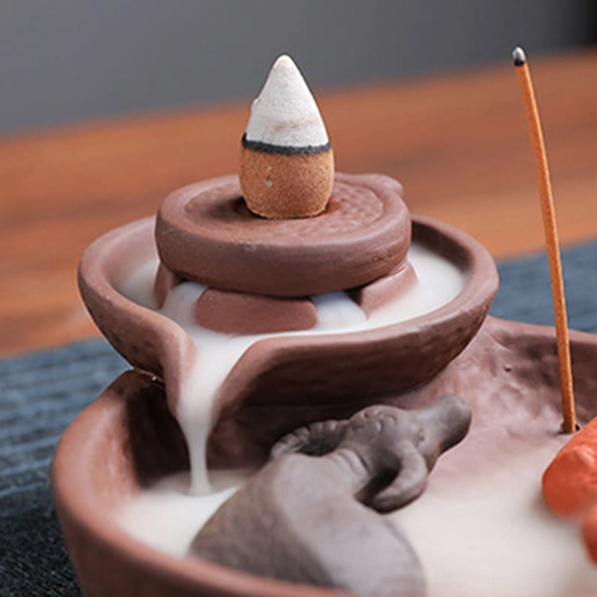 Purple clay backflow incense burner close-up showing flowing smoke waterfall effect with clear holder view and mill design