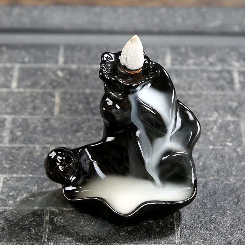 Backflow incense holder demonstrating smoke pooling in tray, waterfall effect on stone tile surface