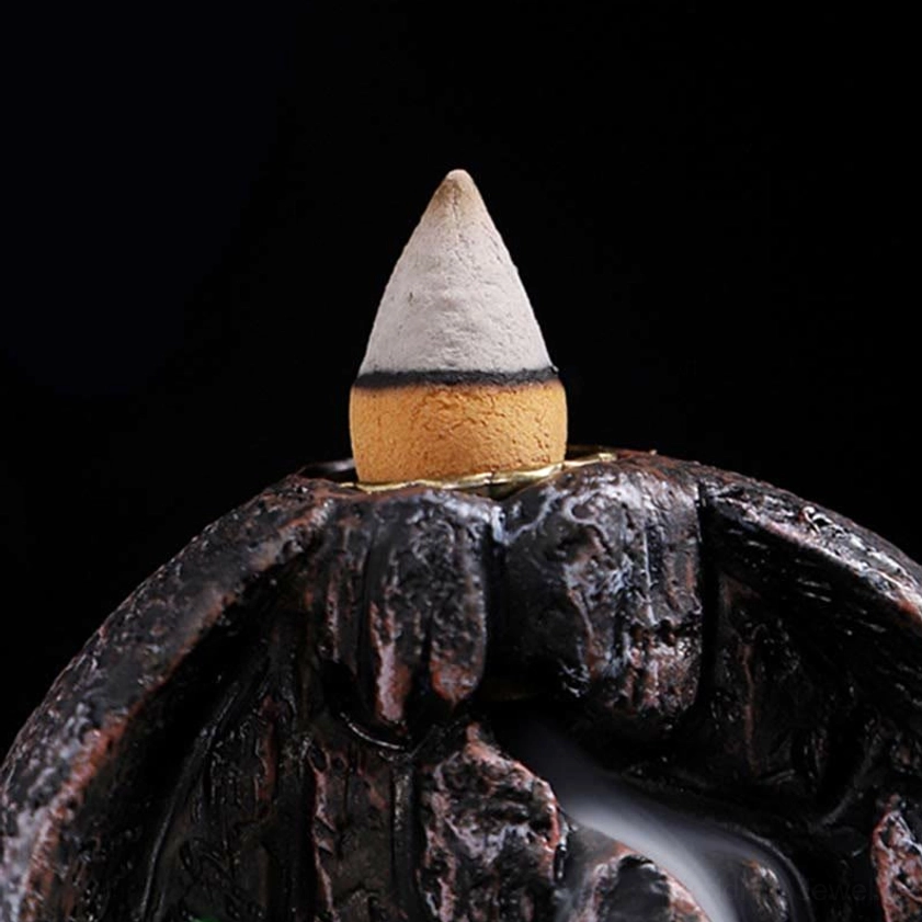 Incense cone with metal fixing ring and wooden base showing backflow smoke cascade effect