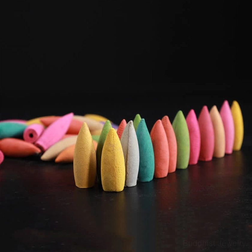 Assorted Buddhist backflow incense cones in neat linear arrangement with gradient color tones against black background, showing product variety