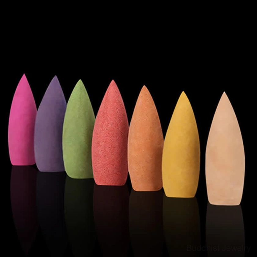 Seven distinct solid color backflow incense cones displayed in row against reflective black background, featuring uniform tapered shape for meditation