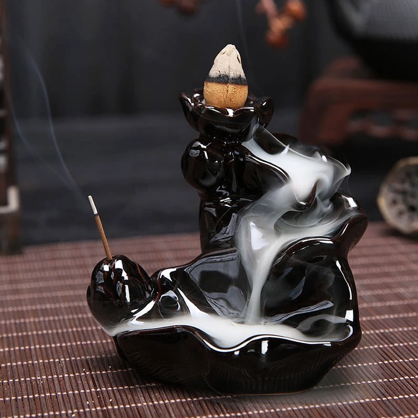 Backflow incense burner in use with flowing waterfall smoke effect, shown on bamboo mat indoor setting