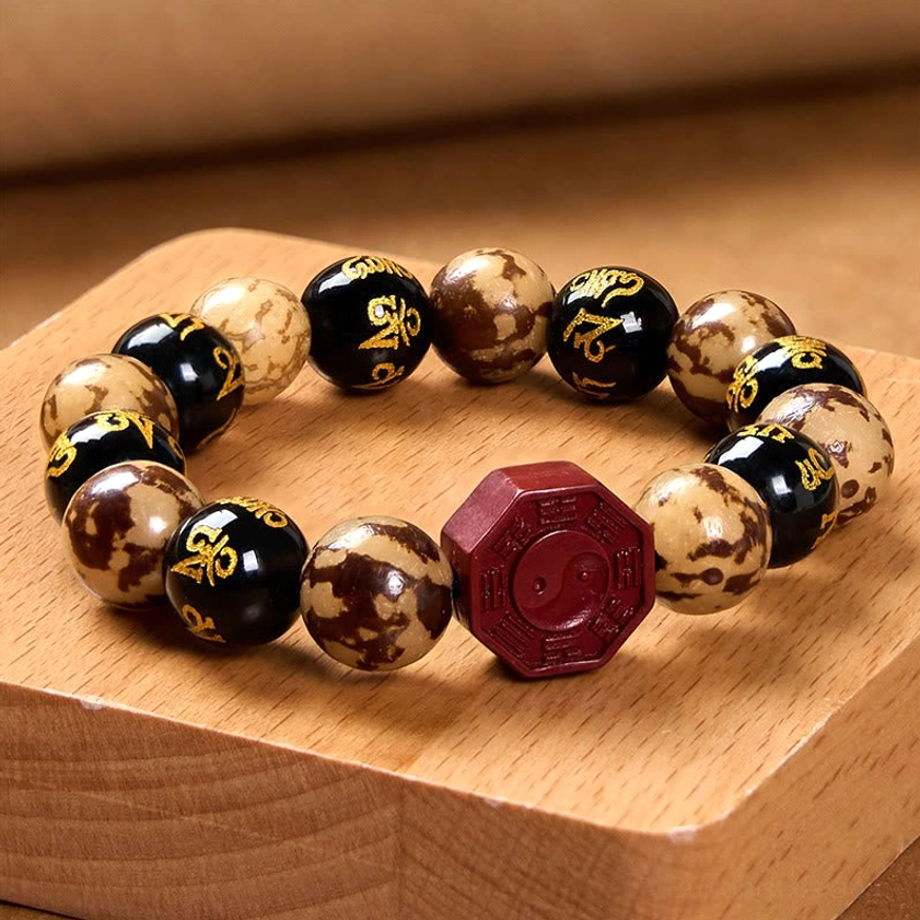 Bagua Yin-Yang prayer bracelet overhead shot displaying red cinnabar focal bead and mixed Bodhi seed beads on wooden block