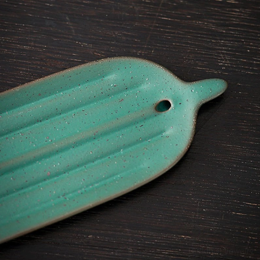 Detail view of bamboo leaf incense holder showing speckled matte glaze and incense stick fixture hole