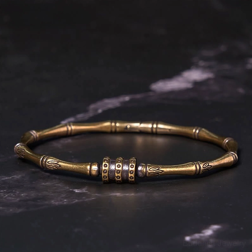 Antique copper brass bamboo lotus bangle featuring stacked central decorative ring and delicate lotus engravings, shown in flat top-down view on marble background
