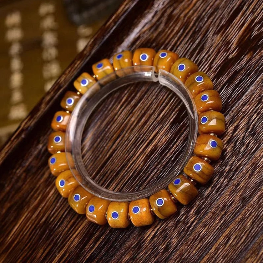 Orange barrel bone beads with lazurite inlays on wooden desk background showing bead texture