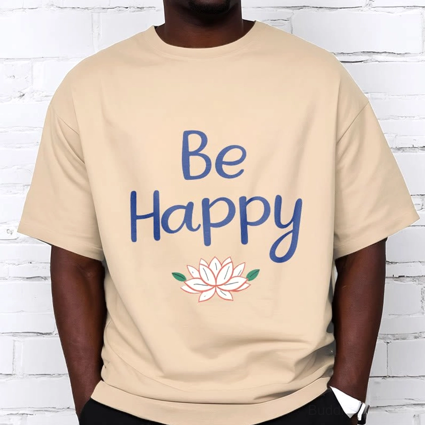 Male model wearing Be Happy lotus tee cream beige, beige cotton relaxed fit t-shirt with blue lotus design, white brick wall