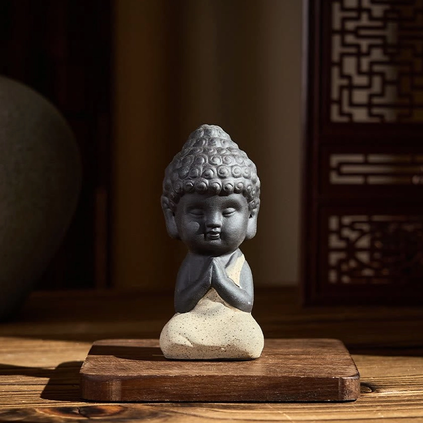 Beige robed Buddha statue with prayer hands gesture, handcrafted purple clay spiritual decoration
