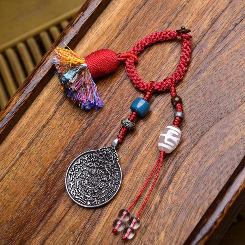 Beige Dzi Bead keychain with red braided rope, hand-painted nine-eye pattern, and silk tassel