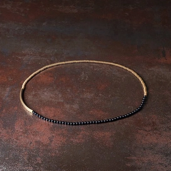 Minimalist single wrap black agate copper Buddhist bracelet flat lay top-down on dark desktop showing simple elegant design with matte black stones and brass
