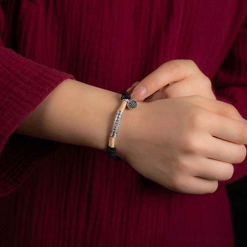 Handmade black braided bracelet worn on wrist with silver mantra charm traditional style