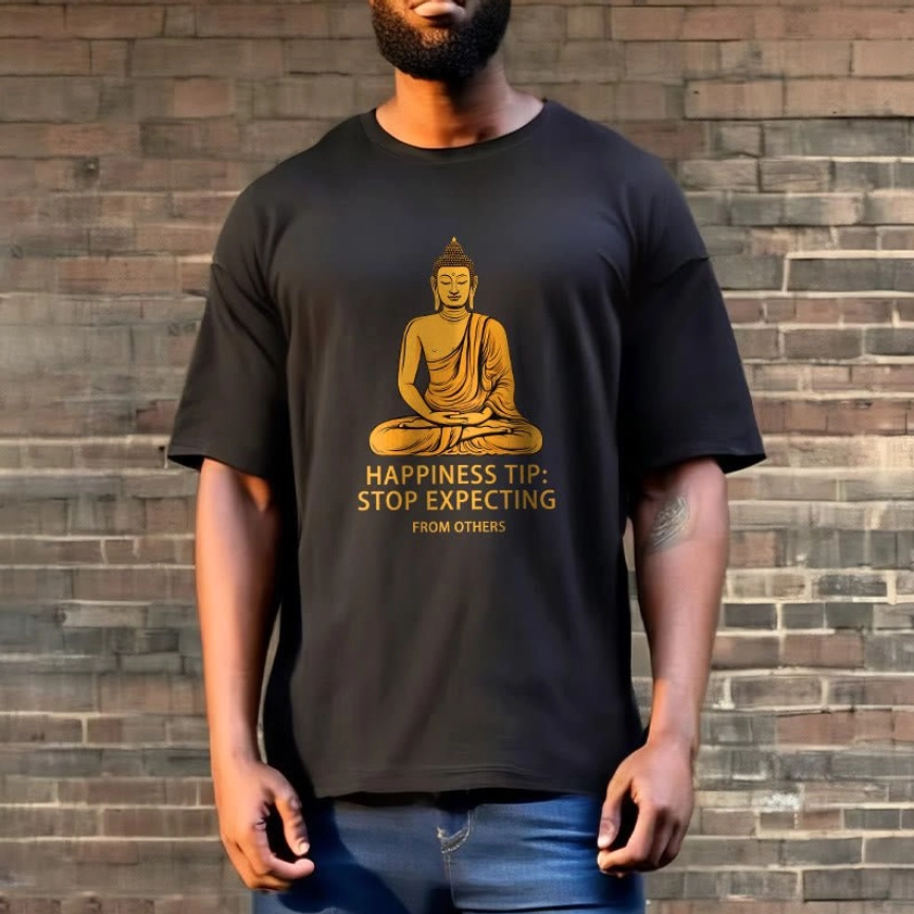 Man wearing black Buddhist mindfulness t-shirt with golden Buddha graphic, casual outdoor brick wall styling