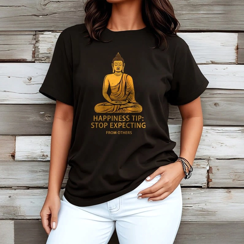 Female model wearing black Buddhist graphic t-shirt with golden Buddha print, paired with white denim jeans