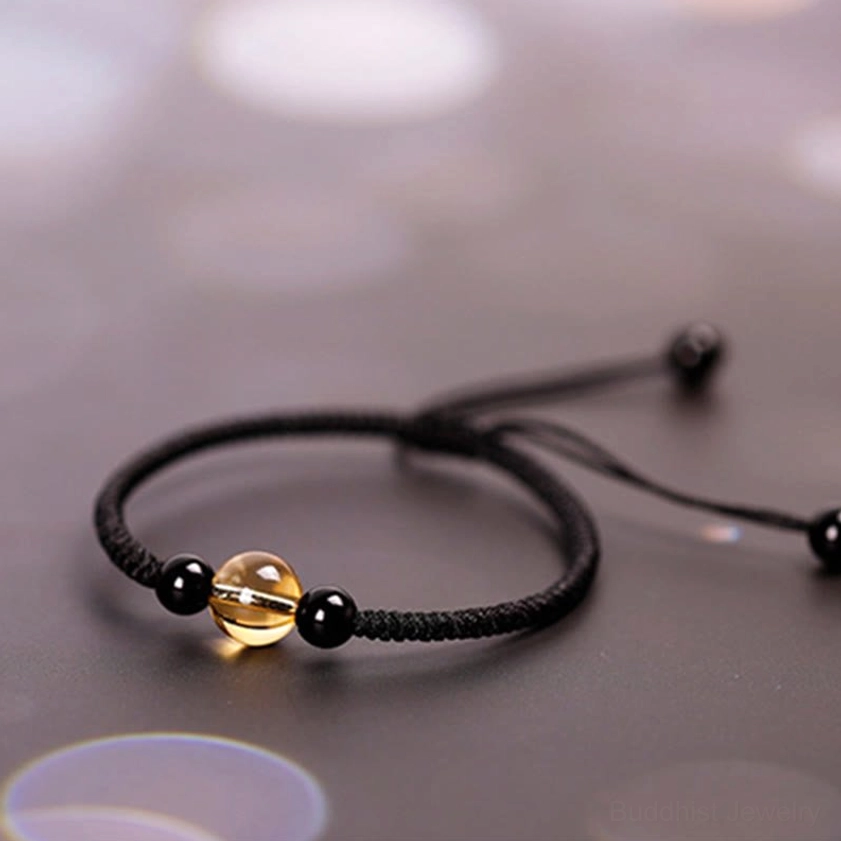 Black woven Buddhist bracelet with citrine center bead flat lay top-down view