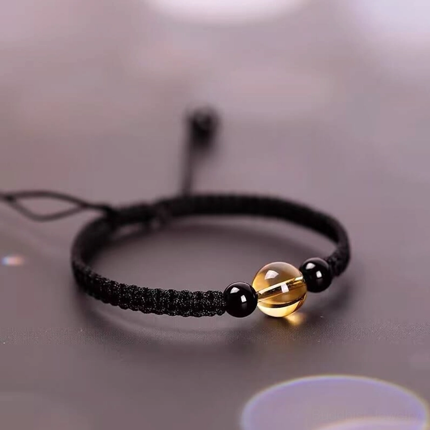Black string Buddhist bracelet with Peace knot and citrine obsidian beads, showing adjustable pull cords
