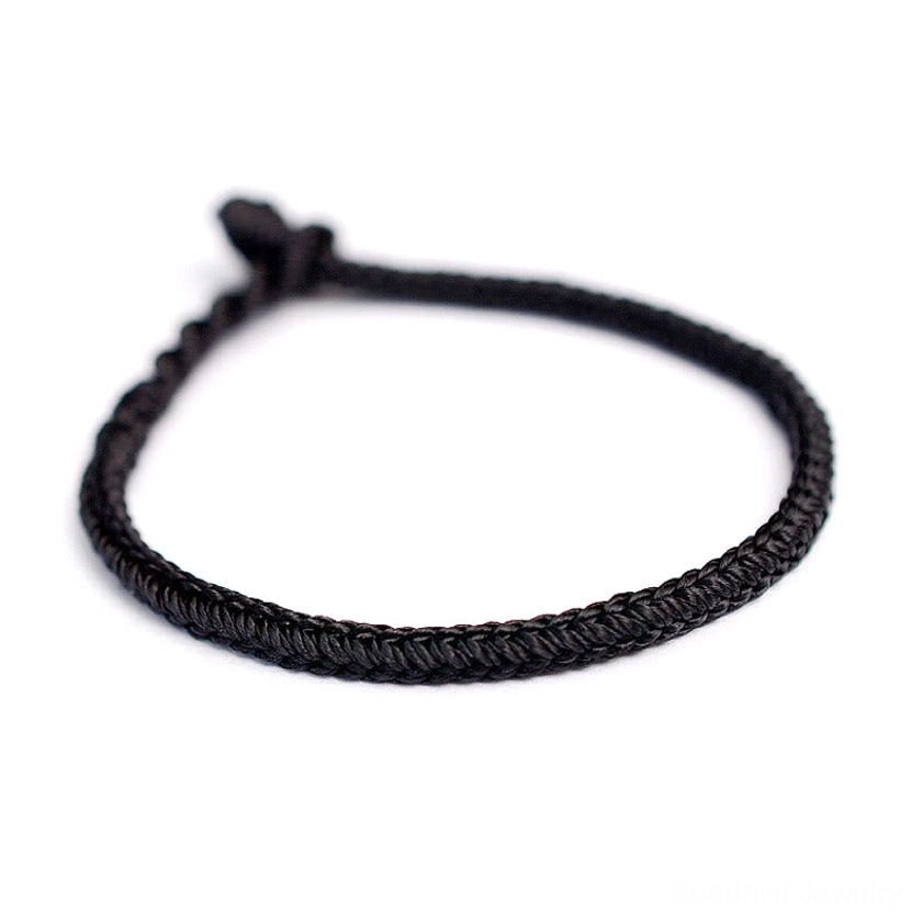 Front view of solid black Buddhist eight-thread braided string bracelet with protective knot on white background