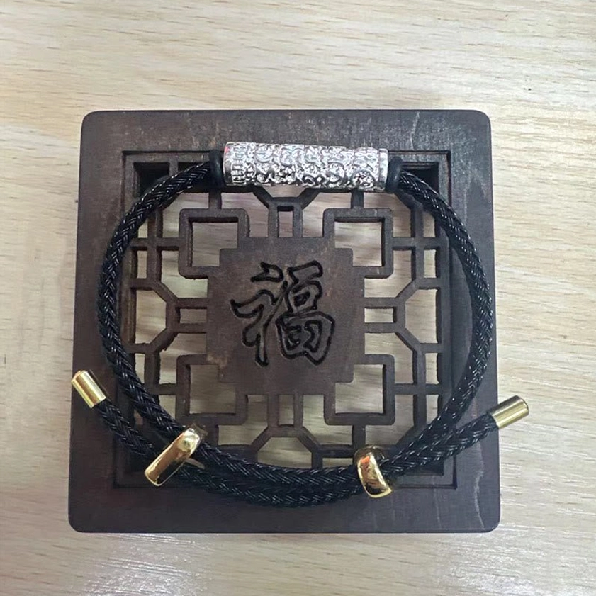 Black protective Buddhist braided string bracelet with silver engraved metal tube detail