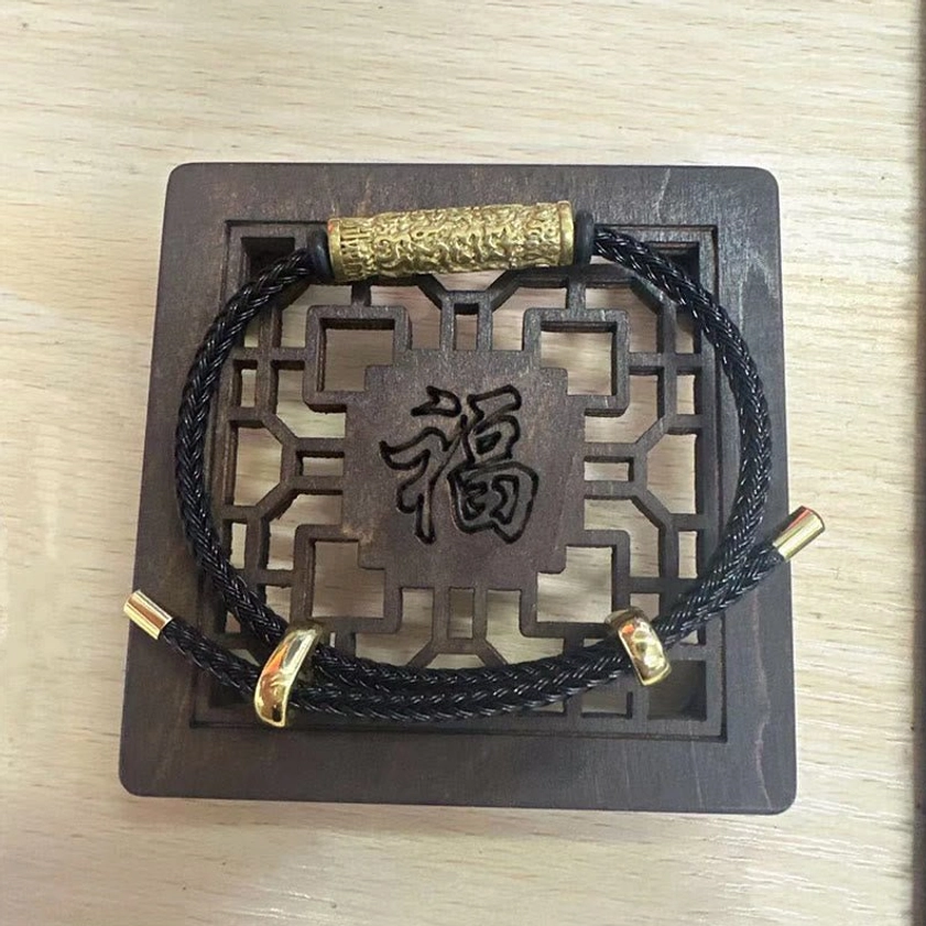 Black woven Buddhist string bracelet with gold engraved copper accents and adjustable buckle