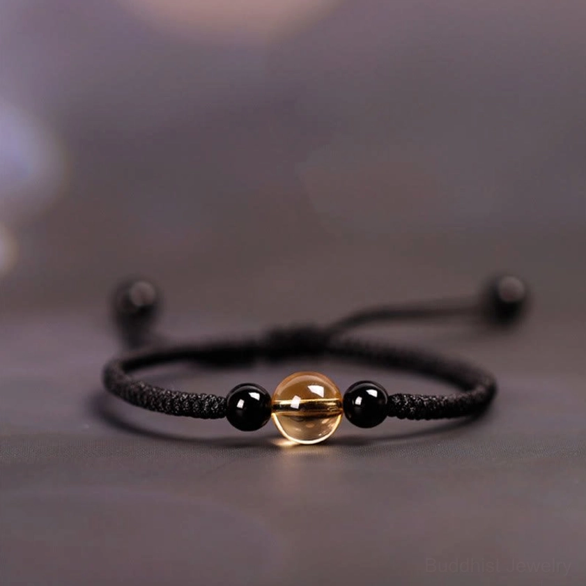 Black cord citrine obsidian Buddhist bracelet with King Kong knot, showing three-quarter view