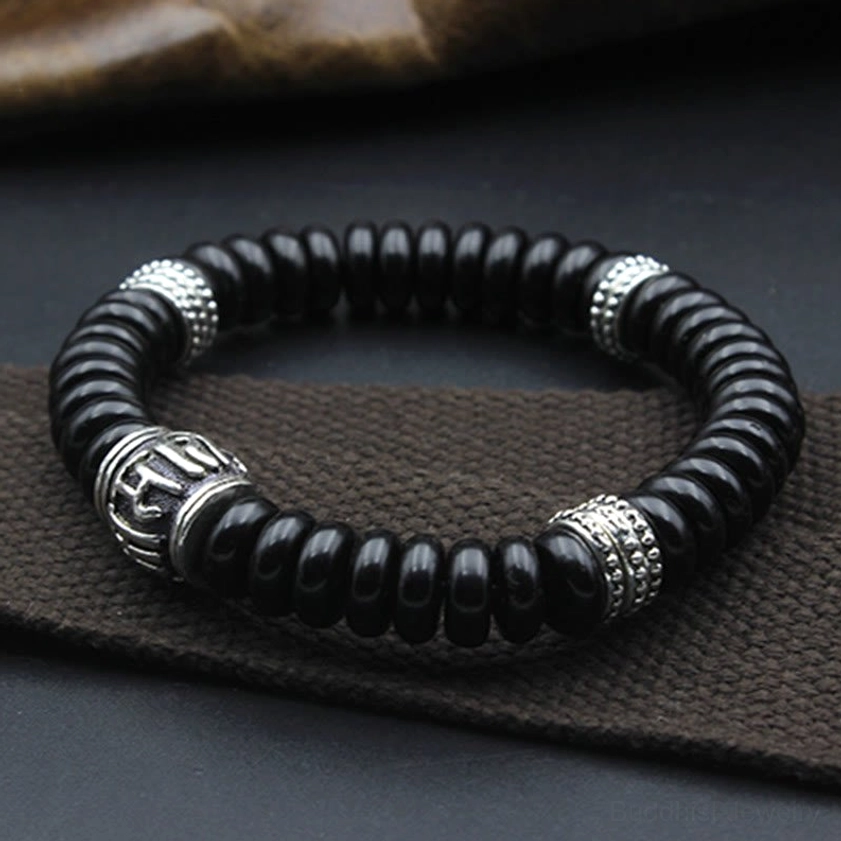 Black coconut shell Buddhist bracelet with silver decorative rings and engraved mantra bead, three-quarter view