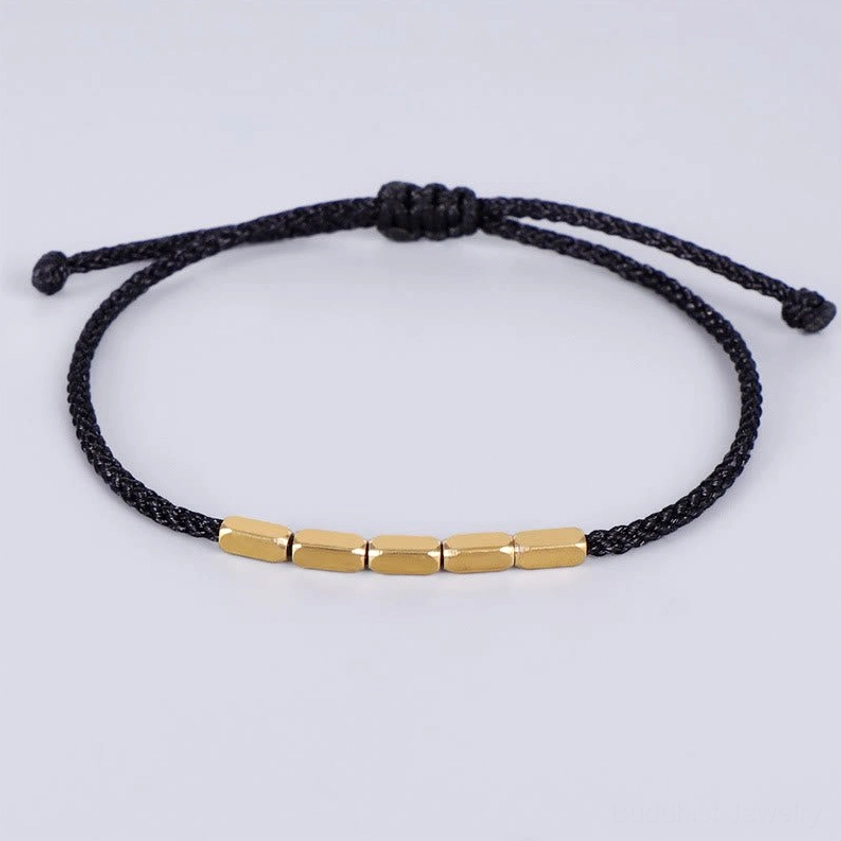 Black braided Buddhist string bracelet with copper beads and adjustable pull-knot closure, flat lay view