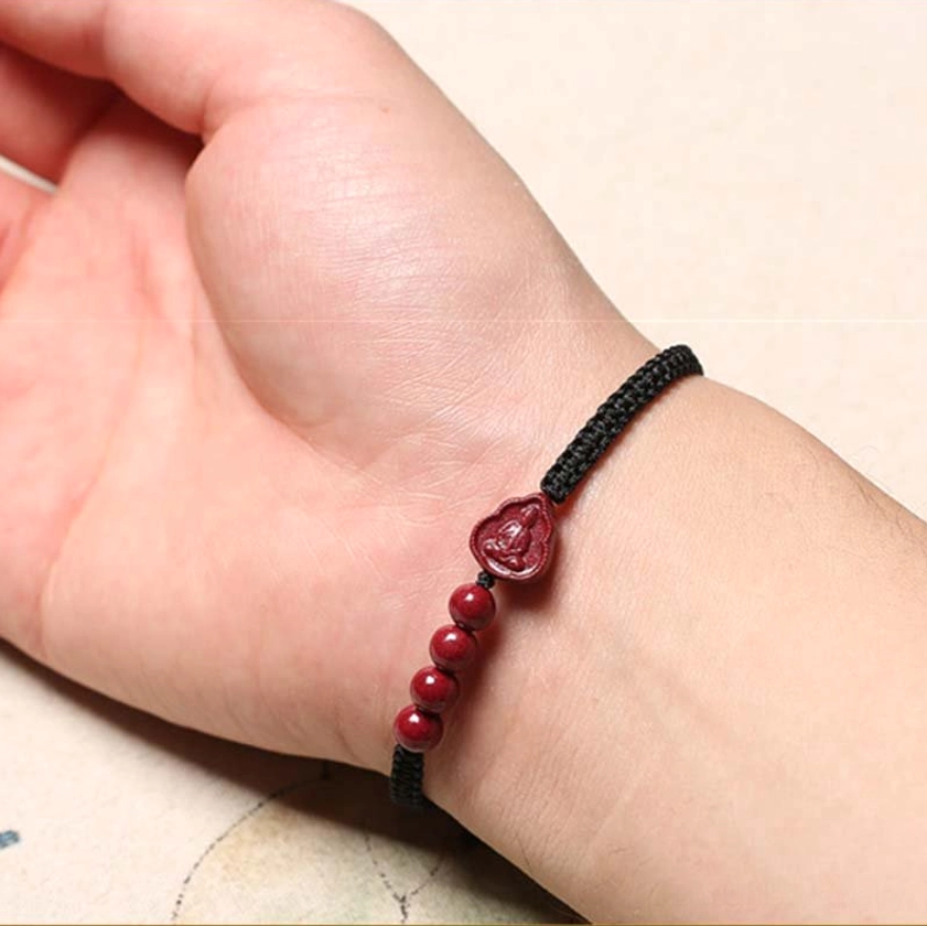 Black string cinnabar Buddha bracelet on wrist, showing comfortable wearing style and spiritual design