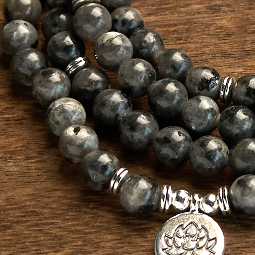 Macro close-up of black glitter stone beads and silver lotus pendant with metal spacers