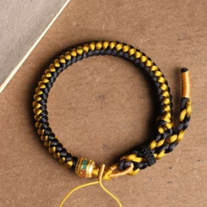 Handmade black and gold dragon scale Om Mani Padme Hum bracelet with engraved mantra bead, overhead flat lay view
