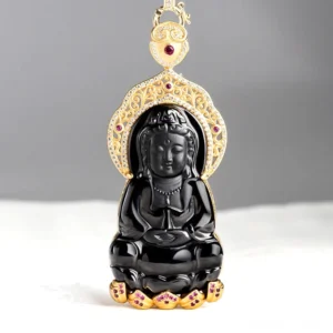 Black jade Avalokitesvara pendant front view showing seated Guanyin with ornate gold-plated filigree frame and red gemstone inlays