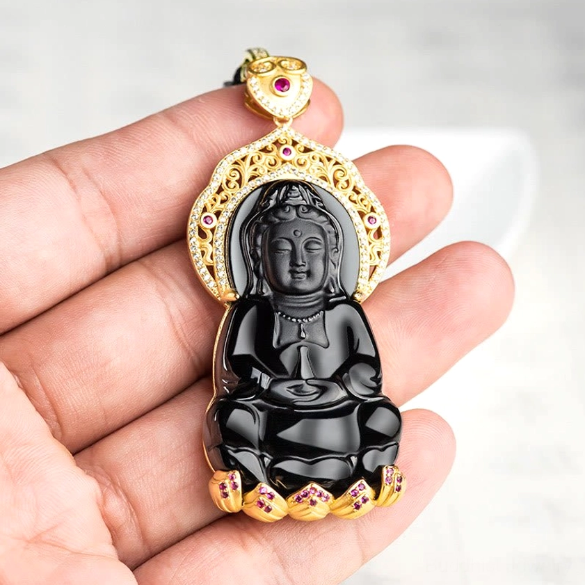 Hand-held black jade Avalokitesvara pendant in adult hand showing size and compact design of spiritual jewelry